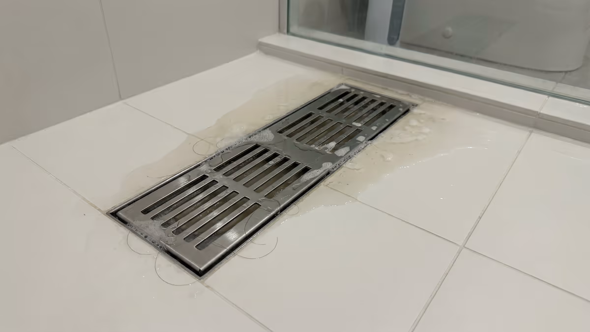 Ralo do box do banheiro entupido com acúmulo de cabelo e sabão